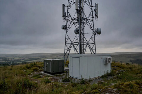 Cell tower with outdoor diesel generator enclosure at dusk