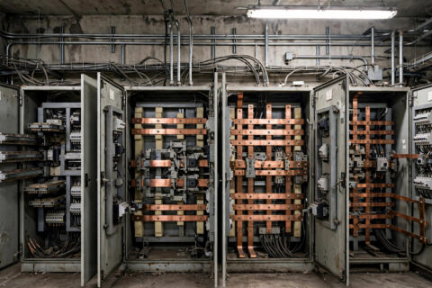 Bypass-isolation automatic transfer switch lineup with doors open in an industrial electrical room, documentary photograph